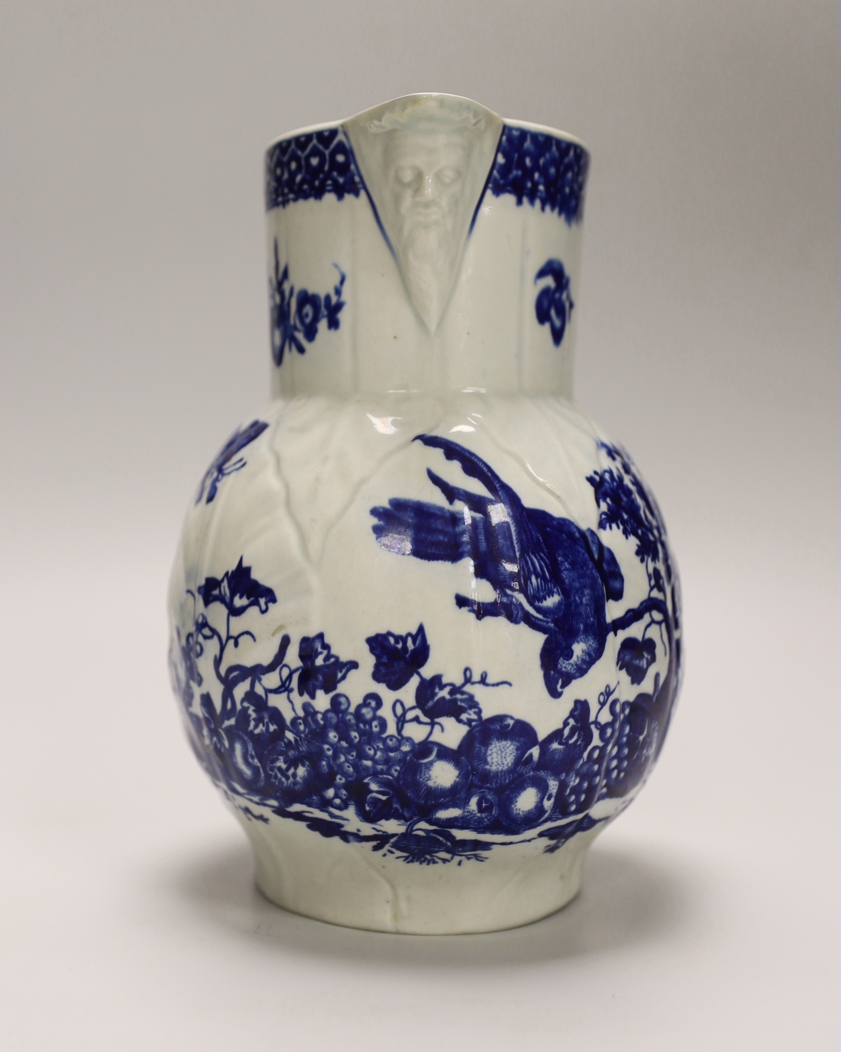 An 18th century Worcester fine mask jug decorated with the Parrot Pecking Fruit pattern, disguised numeral mark, 21cms high